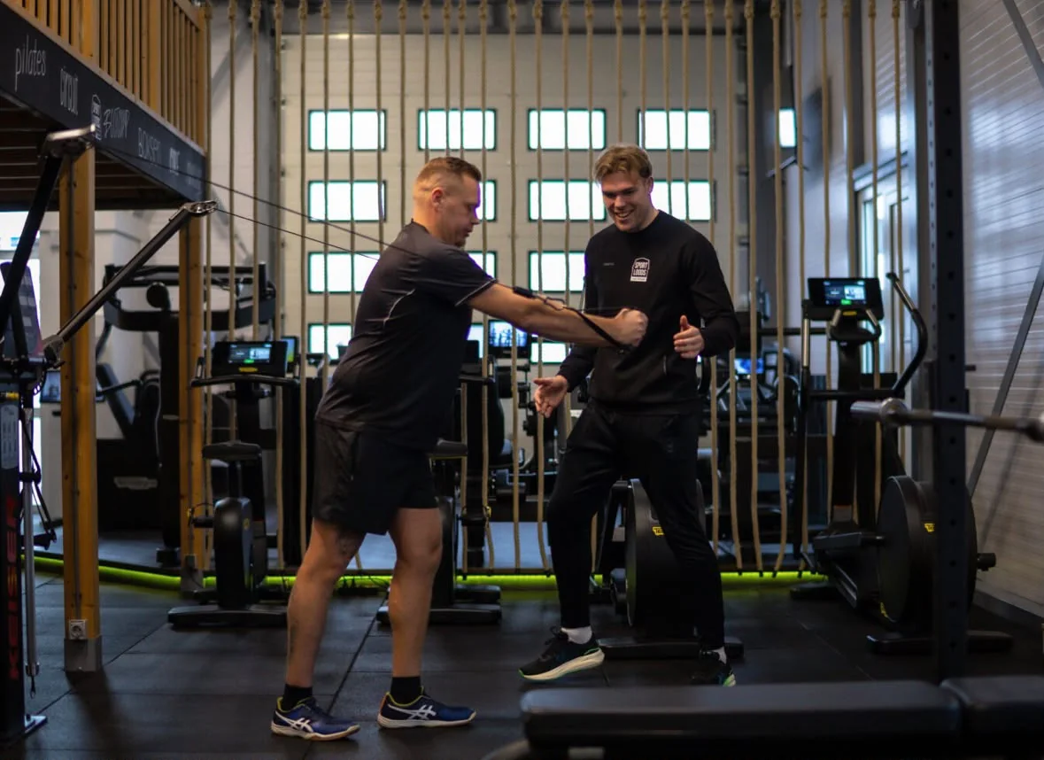 Julius begeleidt een sporter bij een oefening in De Sportloods
